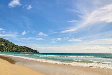 Mavi gökyüzü. Dalgalar deniz. Yeşil ağaçlar. Parlak kum