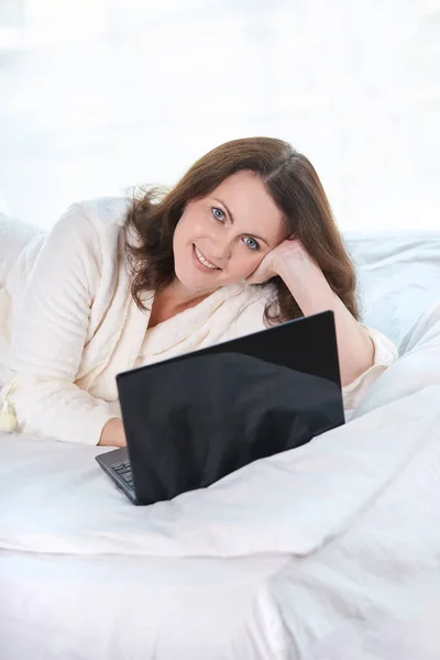 Beautiful girl. Work at home. Black notebook. White Bed