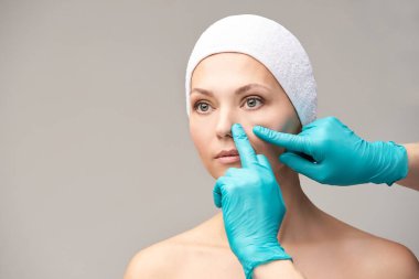 Kadın derma tedavi gençleştirmek. Eldivenli doktor kadın yüzüne dokunur. Kozmetoloji güzel portre. Yüz nosr enjeksiyon hasta