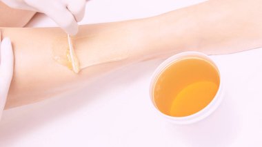 Spa lüks stüdyosunda saç kesimi. Kadın bacakları titreyerek ağda yapıyor. Sıcak şeker. Ağda kabı. Salon kavanozu