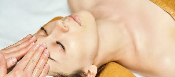 Massaggio viso donna. Massaggiatore viso caldo. Ragazza al salone con le mani del dottore. anti età — Foto Stock
