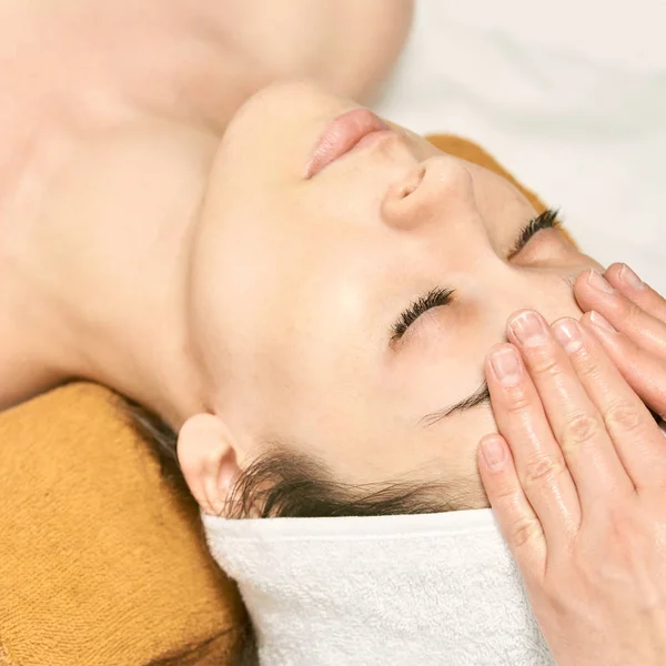 Massage facial femme. Masseur de visage chaud. Fille au salon avec les mains du médecin. anti âge — Photo