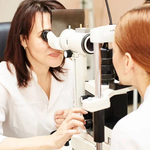Ophthalmologist doctor in exam optician laboratory with female patient. Eye care medical diagnostic. Eyelid treatment Royalty Free Stock Photos