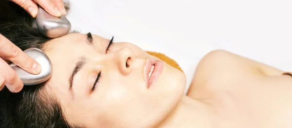 facial ice stick massage. Hot face masseur. Girl at salon with doctor hands