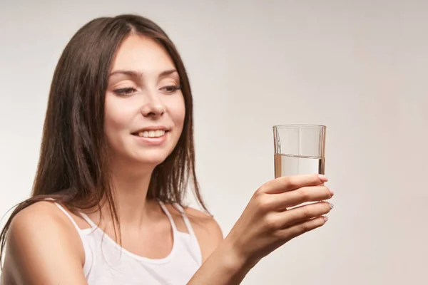 Gadis muda yang cantik memegang gelas air. Hydrate wajah perempuan. Wanita bahagia rutin . — Stok Foto