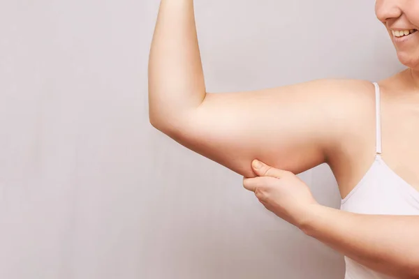 Young woman pinch fat arm. Hand pinching body. Fenale person showing overweight