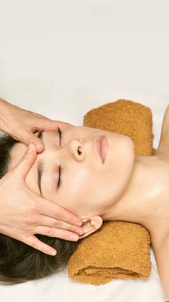 Massaggio viso donna. Massaggiatore viso caldo. Ragazza al salone con le mani del medico — Foto Stock