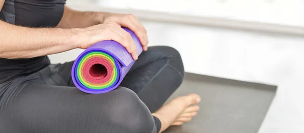 Pessoa segurando tapete de ioga no joelho. Conceito de equipamento desportivo — Fotografia de Stock