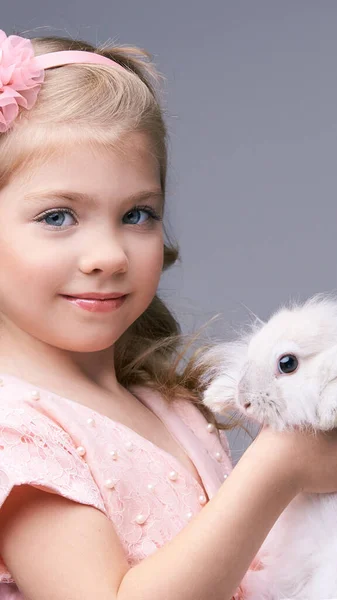 Csinos kislány, szőrös nyúl babával a kezében. Fehér aranyos kisállat stúdió. Boldog húsvétot! — Stock Fotó