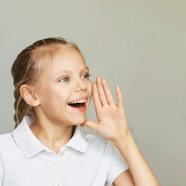 Μια μικρή γυναίκα να χαμογελάει. Πλευρά φωνάζοντας χέρι κοντά στο κεφάλι. Γυναικείο παιδικό πορτρέτο — Φωτογραφία Αρχείου
