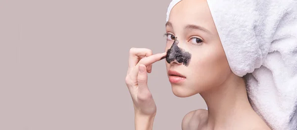 Young girl applying black face mask — Stock Photo, Image