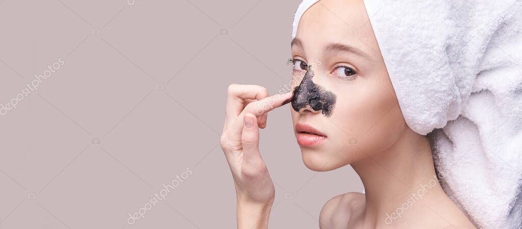 Young girl applying black face mask