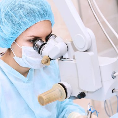 Mikroskobun yanındaki ameliyathanede bayan doktor.