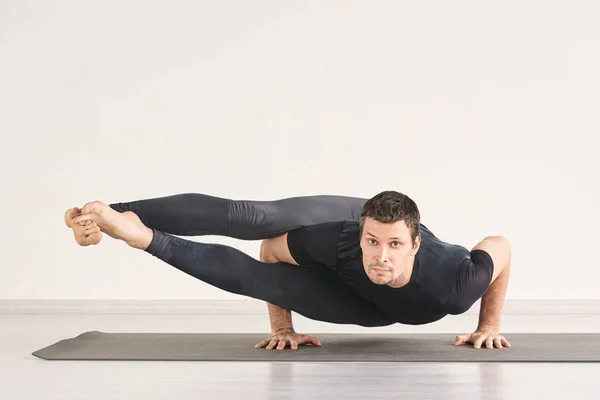 Um homem forte está em Astavakrasana. Exercício de ioga fitness . — Fotografia de Stock