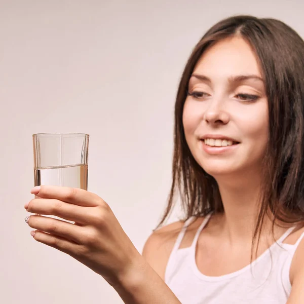 Jovem menina beatiful segurar vidro de água. Hidratar o rosto feminino. Mulheres felizes dentro de casa — Fotografia de Stock