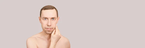 Man doing home skin care routine. Cotton pad near male chin