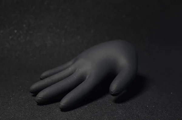 Siyah arka planda tek kullanımlık siyah eldivenli güzel bir 3D el. Kavram: 3d eldivenli el karanlıkta belirir. Metin için boşluk var.