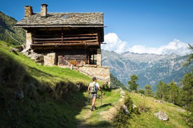 Güneşli güzel bir günde, antik Walser eviyle panoramik bir patikada Alpler 'e yolculuk yapmak. Aosta Vadisi, İtalya