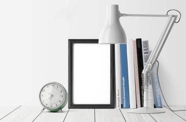 Kitaplar ve çalar saat masa lambası ile yığını ile boş fotoğraf çerçevesi
