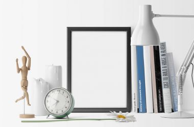 Kitaplar ve çalar saat masa lambası ile yığını ile boş fotoğraf çerçevesi