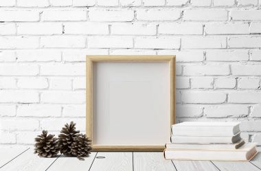 çam kozalakları ahşap zemin üzerinde ve kitaplar ile boş fotoğraf çerçevesi 