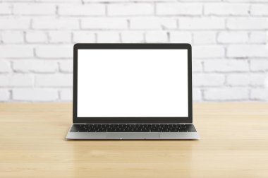 ahşap masa beyaz boş ekranda arka plan üzerinde tuğla duvar ile olan dizüstü bilgisayar 