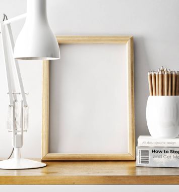 boş fotoğraf çerçevesi ile masa lambası ve yığın tablo kalemleri ile kitap 