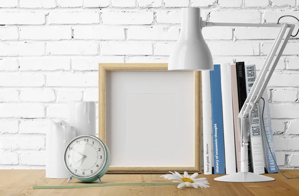 Kitaplar ve çalar saat masa lambası ile yığını ile boş fotoğraf çerçevesi