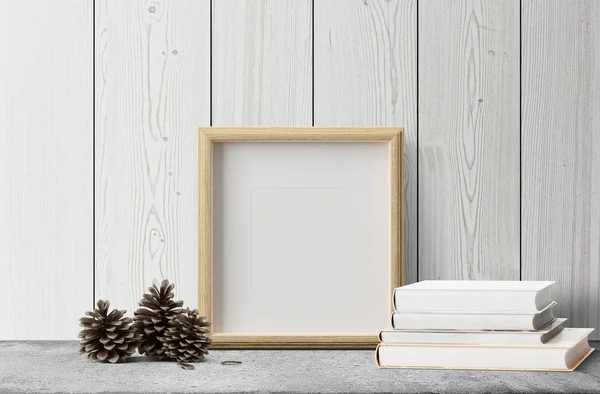empty photo frame with books and pine cones on grey floor