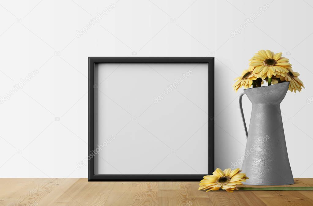 empty photo frame with yellow daisies in metal garden jug 