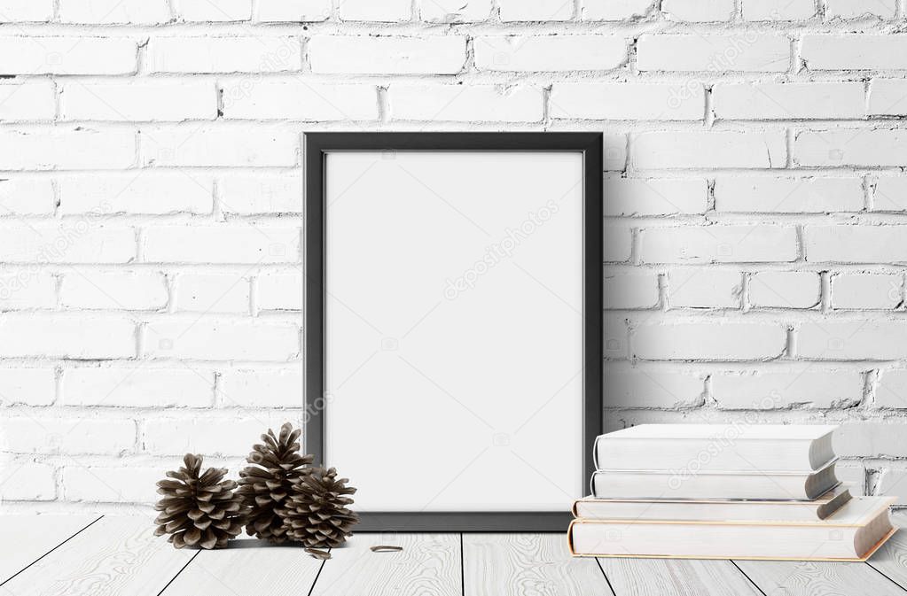 empty photo frame with books and pine cones on wooden floor 
