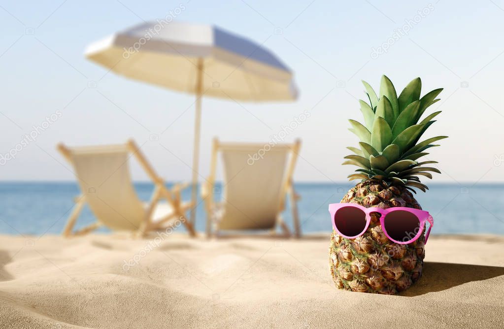 ripe tropical pineapple in sunglasses on sandy beach, vacation concept 