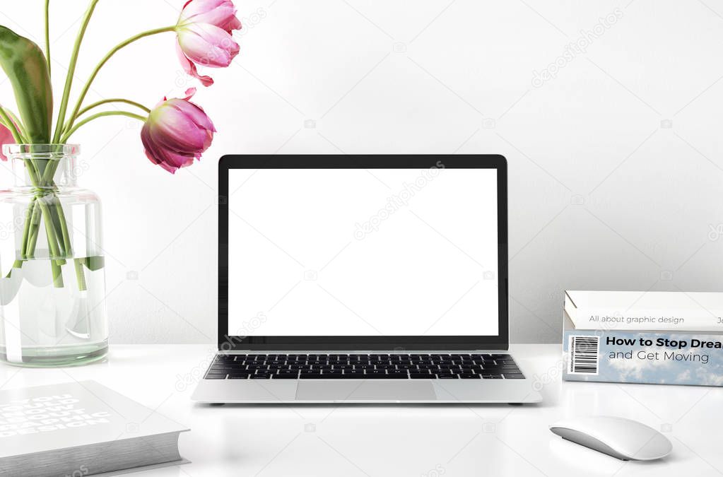 laptop with flowers in vase and books on desktop 