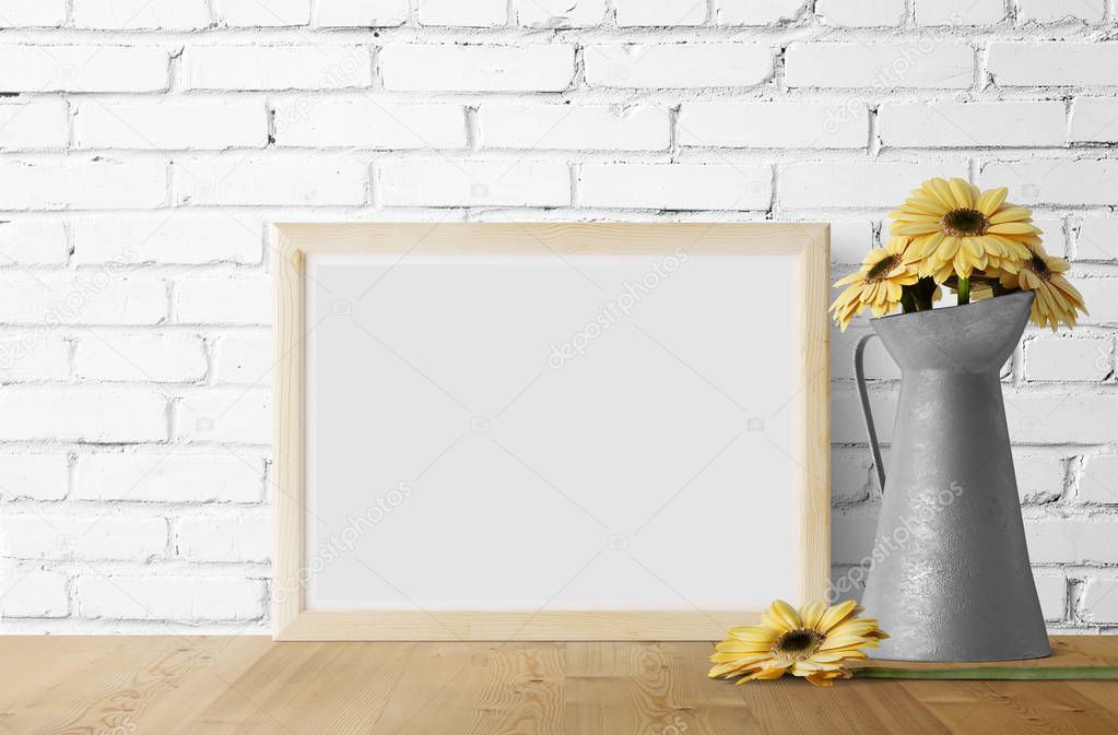 empty photo frame with yellow daisies in metal garden jug 