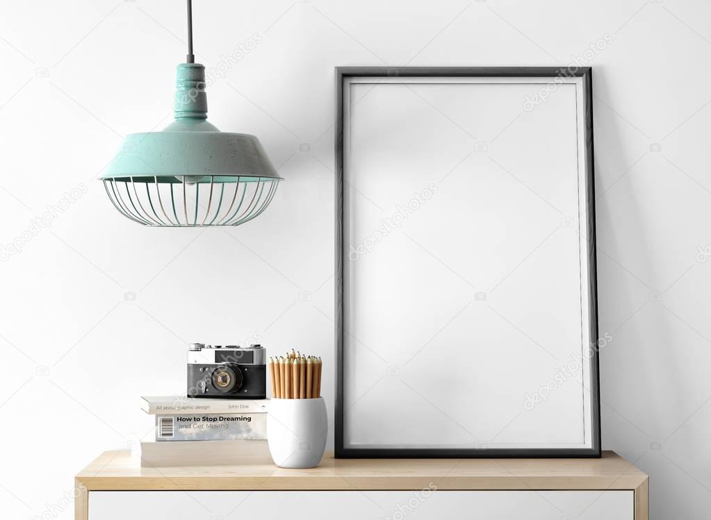 empty photo frame with camera on pile of books and pencils on table 