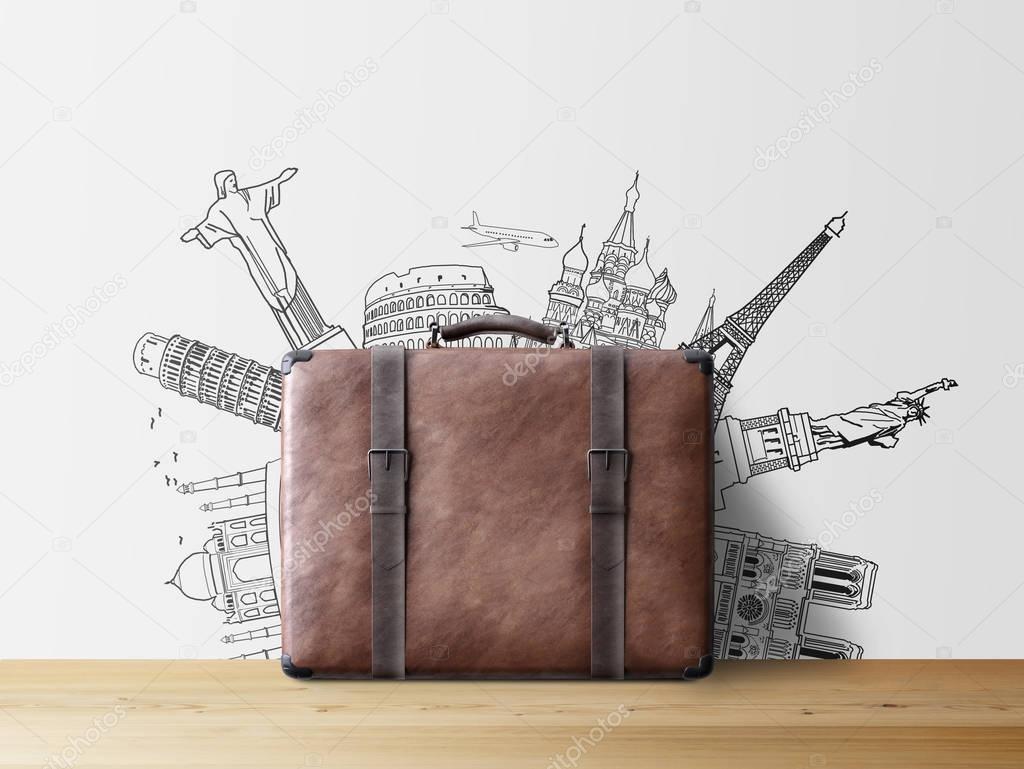 brown valise with sketch of popular tourist attractions on wall, travel concept 