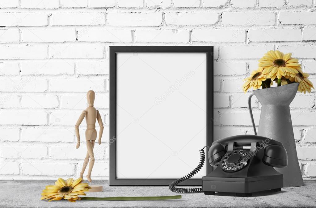 empty photo frame with yellow daisies in metal garden jug and retro phone
