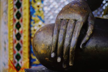 Thai tapınağındaki Buda heykelinin elinde çiçek çelengi 