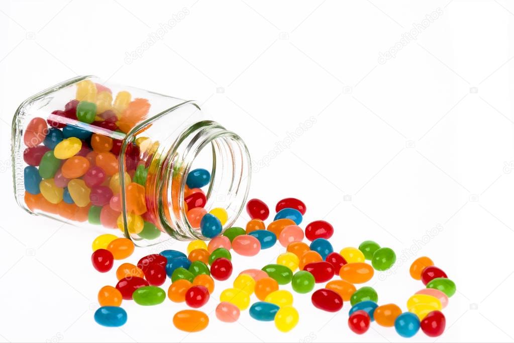 Jelly Beans candy spilled from glass jar isolated on white backg