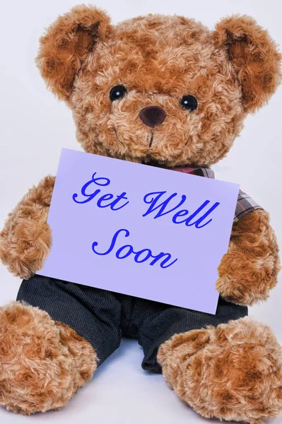Teddy bear holding a purple sign that says Get Well Soon — Stock Photo, Image