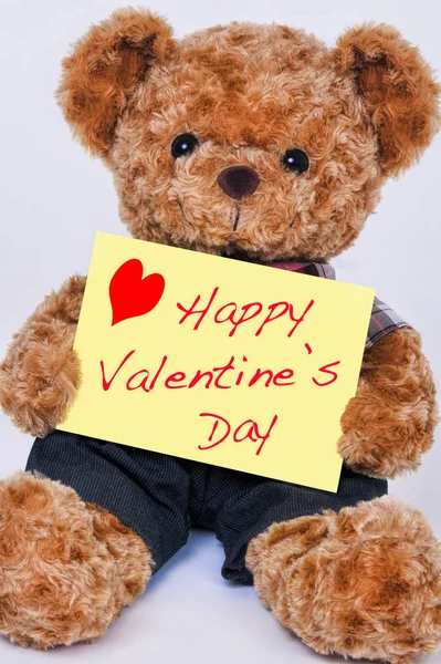 Happy Valentine's Day diyor sarı bir işaret tutan bir oyuncak ayı
