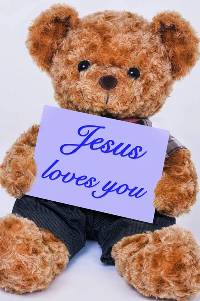 Urso de peluche segurando um sinal roxo que diz que Jesus te ama — Fotografia de Stock