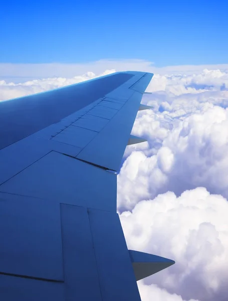 Airplane wing as viewed from window showing clouds and blue sky — Stock Photo, Image