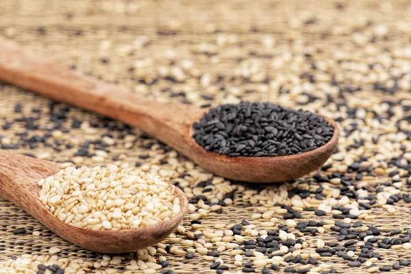 Wooden spoon full of both healthy sesame and black sesame seeds