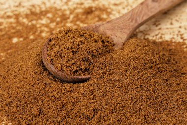 Tahta arka planda koyu kahverengi şeker dolu bir kaşık.