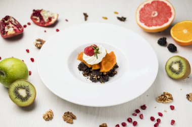 Çilekli tatlı, balkabağı ve krema büyük beyaz bir tabakta meyve ve böğürtlen kompozisyonu ile