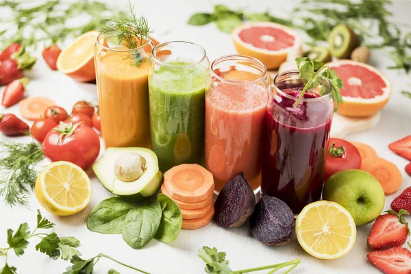 freshly squeezed juice, fruit and vegetable smoothies in glass glasses on a white table decorated with a composition of fruit