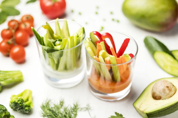 salad of fresh vegetables light salad in a glass on a white table with a composition of tomatoes, avocado, parsley, cucumbers, peas, broccoli