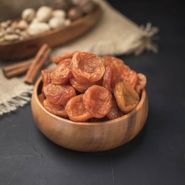 Kare bir ahşap kasede kurumuş meyve, koyu bir arka plan ve çuval bezi.