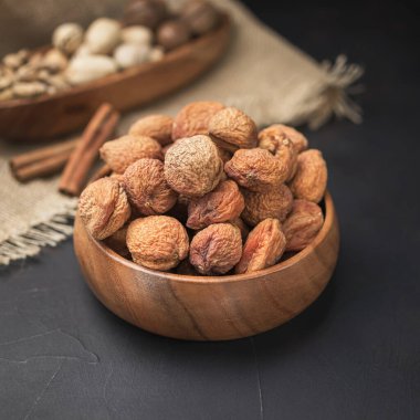 Kare bir ahşap kasede kurumuş meyve, koyu bir arka plan ve çuval bezi.